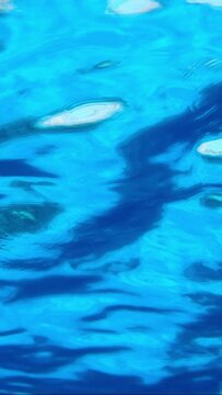 VERTICAL VIDEO, Underwater view on calm surface of blue water. Natural background with surface of blue water. Texture of blue water on surface. Close-up, Slow Motion