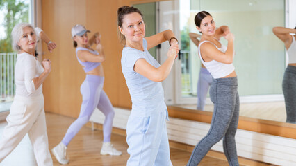 Active middle-aged woman practicing aerobic dance in training hall during fitness dance classes....