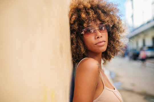 Cuban female leaning on wall and looking at camera