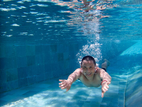 Asian man swimming happily in the pool