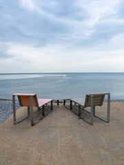 Fototapeta na wymiar Benches for lying by the sea. Sun loungers in the park against the background of the sea.