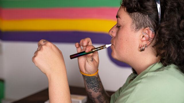 Young tattooed woman taking a drag from vape pen
