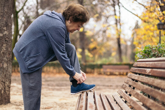 Senior woman tying her shoelaces for exercise in the park
