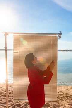 A girl hides from the sun behind blinds in autumn on the beach