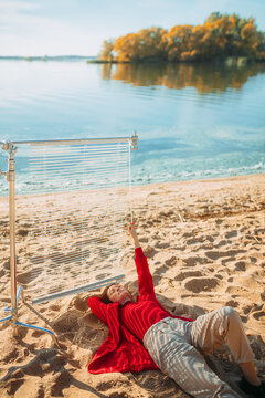 A calm girl lies relaxed on the sand near the lake with blinds