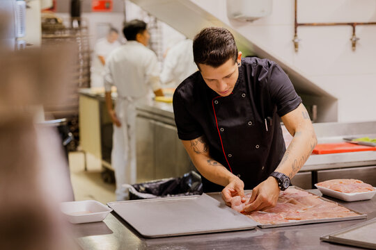 Young cook arranging meat on tray