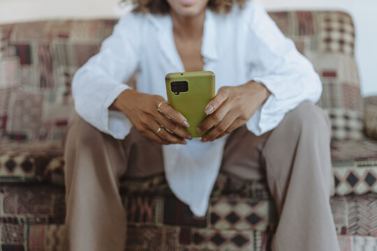 Crop lady using cellphone on sofa