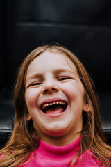 Photography, close-up portrait of a beautiful little red-haired laughing girl, a child with an open mouth. The concept of emotions, laughter, joy.