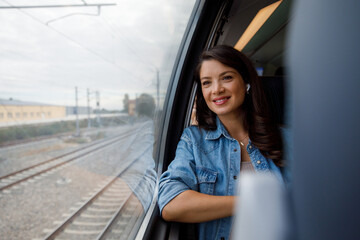Smiling thoughtful commuter looking through window from train 