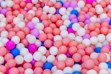 Background, texture of colored, multi-colored round plastic small balls on the playground for children's games. Photography, top view, copy space, childhood concept, macro, wallpaper.