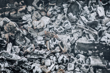 Close-up photo of smoldering gray coals, close-up burnt ash in a campfire, fire with smoke.