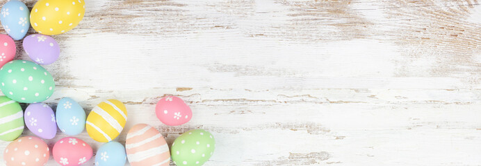 Pastel colored Easter egg corner border. Top view over a rustic white wood background. Copy space.