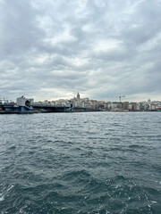 Fototapeta premium Istanbul, Turkey. Karaköy,Istanbul with Galata tower, Galata bridge and architecture on cloudy day. Scenic view of Karakoy quarter and Galata Tower from Golden Horn Bay in winter twilight