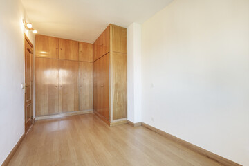 Empty white walled room with a custom made wardrobe covering two walls in an L shape