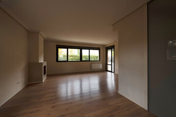 Empty living room with fireplace in a corner next to windows with access door to a patio