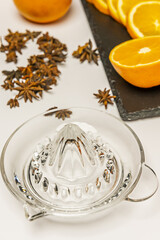 A still life with a clean glass juicer ready to squeeze split oranges