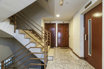 Interior staircase of an urban residential apartment building with an elevator with a brown door