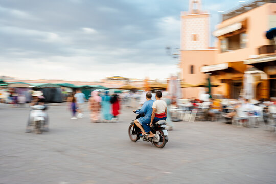 Two men on mopeds arrive at the main square of Marrakech