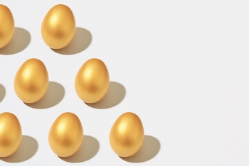 Golden Easter eggs on white background with copy space, minimal isometry pattern.