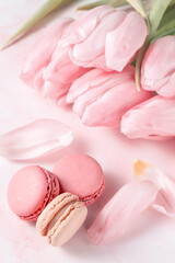 French sweet cookies macarons macaroons and bouquet of tulip flowers on marble background.