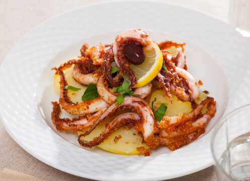 Delicious cooked squid or octopus tentacles with lemon and parsley on a plate