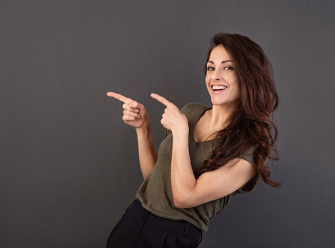 Beautiful positive makeup happy woman in greel fashion t- shirt showing and demonstrate idea gesture by two fingers on empty copy space background.