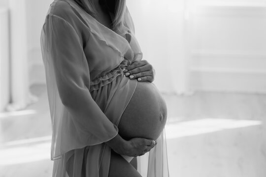 Attractive pregnant woman in dress. Motherhood and healthcare concept. Black and white photo