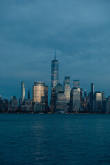 Naklejka premium New York harbor and skyline with Manhattan skyscrapers and One World Trade Center in dusk.