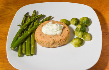 salmon burger top with  tarter sauce with a side of asparagus