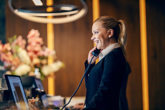 A happy receptionist is answering calls at reception.