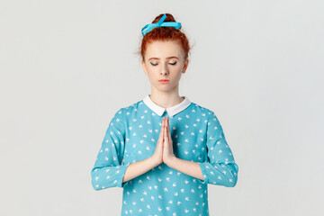 Portrait of calm peaceful attractive ginger woman with bun hairstyle, practicing yoga, keeps eyes...