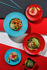 Composition with healthy salads , tartar, seafood salmon and tuna, Edible Green Algae Asian food on colorful background , chopsticks, top view, sunlight with harsh shadows, top view