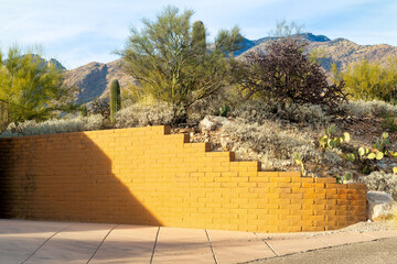 Yellow brick retaining wall wrapping around small hill in front yard of house or home in a desert...