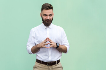Portrait of attractive cunning bearded businessman wearing white shirt schemes something, keeps...