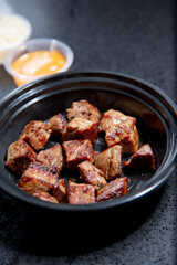 A view of a plastic container of chopped steak cubes.