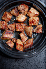 A top down view of a plastic container of chopped steak cubes.