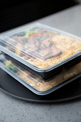 A closeup view of a stack of food orders packed inside plastic to-go containers on the counter.