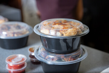 A view of several plastic to-go containers ready for pick up on a restaurant counter.