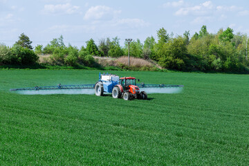 Farmer applying a fertilizer or herbicide chemical to his field with the help of tractor.