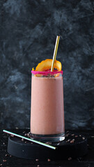 Pink smoothie with an orange peel and straw