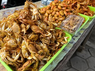 Local street food vendor selling deep fried crispy baby crab and sand dweller or isopod on the Parangtritis Beach, Indonesia.