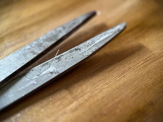 Selective focus view of scissor with dirty blade on wooden background. Macro photography.