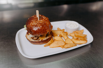 A big tasty hamburger and fries on a metal table background