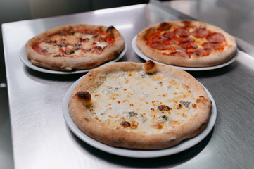 cheese, meat and tomato pizza on a metal table. italian pizza