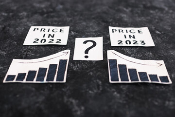Fototapeta premium charts comparing prices going up in 2022 and potentially going down in 2023 with question mark, interest rates and cost of living concept