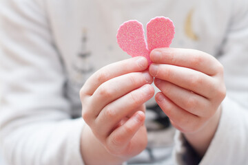 manos de niña sujetando corazón rosa de goma eva roto, en su casa. San valentin. Horizontal. sin...