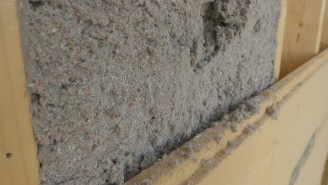 CLOSE UP: Detailed shot of modern environmentally friendly housing insulation covering a house. Grey ecofriendly cellulose insulation fills up a frame on a wooden wall of CLT house under construction.