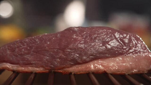  Whole picanha roasting on the grill with strong fire and flames.