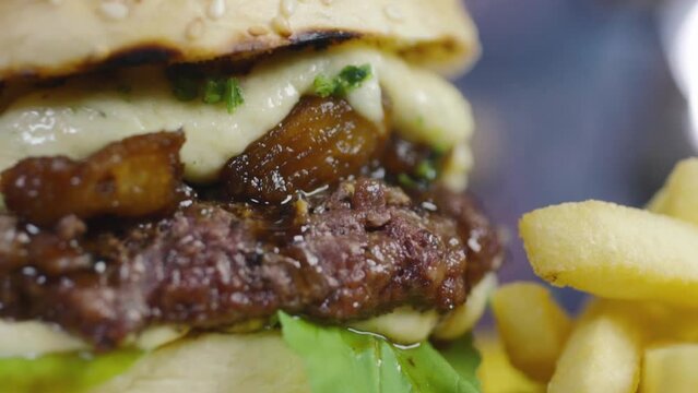 Super close of a tasty burger with pineapple caramelized with brown sugar and whiskey, aligot and arugula on a lovely sesame bun