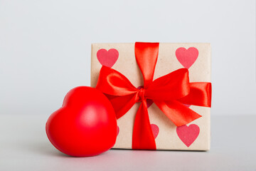 gift box with red bow and red heart on colored background. Perspective view. Flat lay